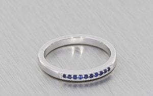 White gold wedding band set with blue sapphires and finished with beaded edges